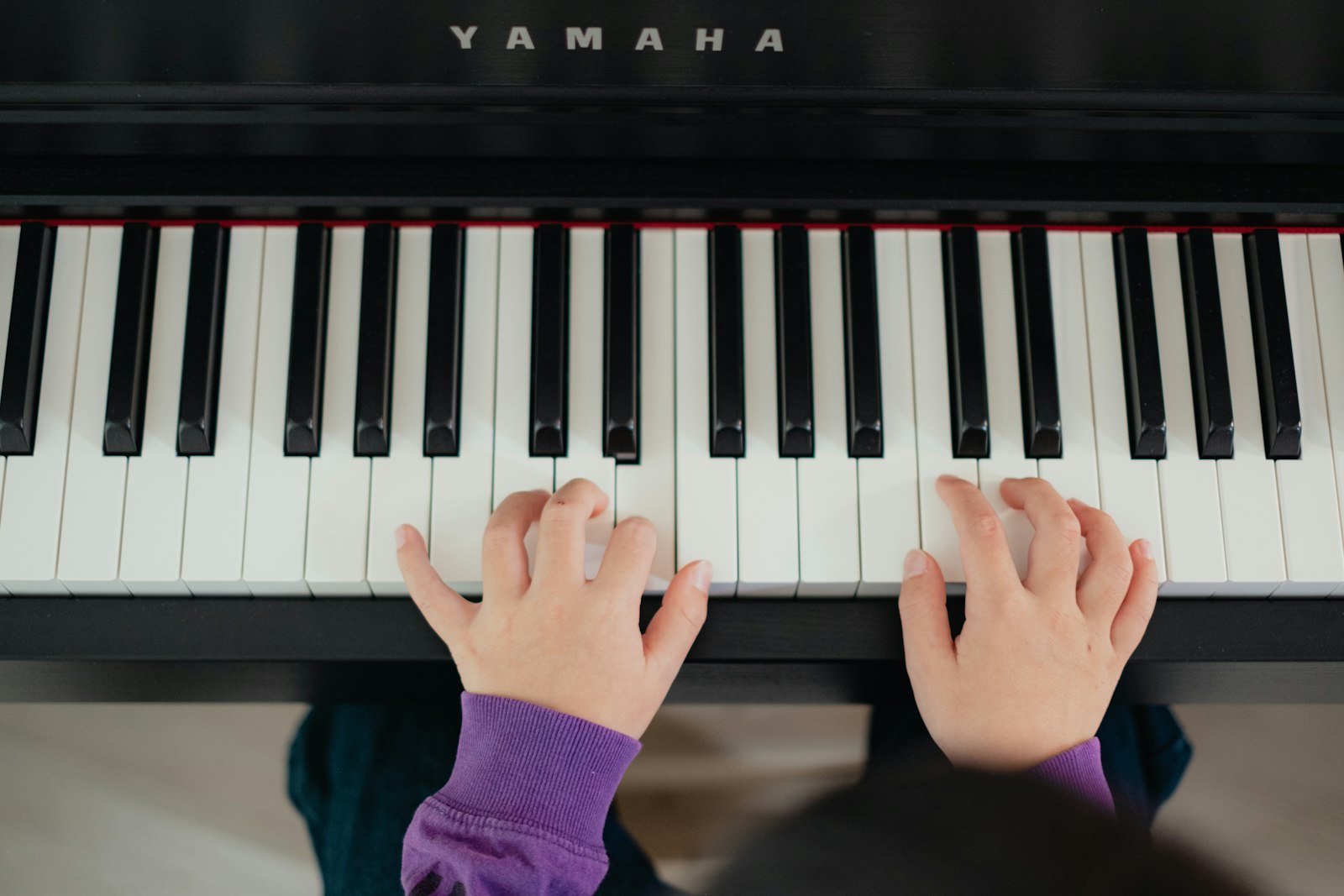 A child's hands on the keys of an upright piano
