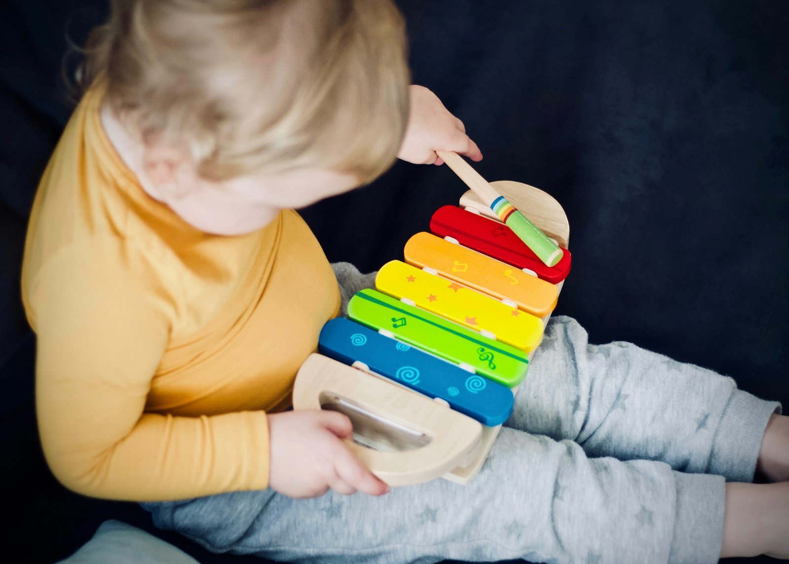Young child playing a colourful wooden xylophone